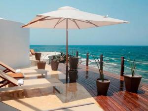 une terrasse avec des chaises et un parasol et l'océan dans l'établissement Isla Pelícano, à Isla Grande