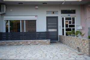 a building with a black door and a stone patio at Διαμέρισμα με αυλή in Nafpaktos