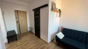 a living room with a blue couch and a hallway at ApartmentsByMatyrafa-IX in Tarnowskie Góry