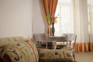een woonkamer met een tafel met stoelen en een vaas met bloemen bij Anna Apartments in Lviv