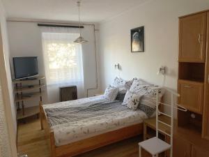 a small bedroom with a bed and a television at Fészek Apartmanház in Tapolca