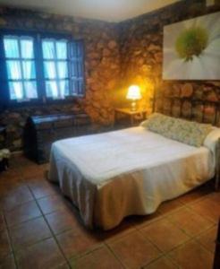 una camera da letto con un letto e un muro di pietra di La Cabaña de Piedra a Ruidera