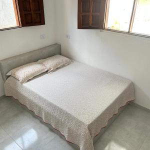a small bed in a room with two windows at Casa Praia BRISAMAR in Maragogi