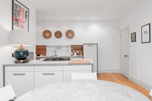 a kitchen with white cabinets and a stove top oven at Super Central - Georgian Double Upper Flat with Castle Views in New Town in Edinburgh +17 photos
