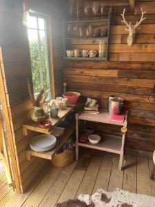 a kitchen with wooden walls and a table with plates at The Hen House Shepherds hut with hot tub in Chittoe