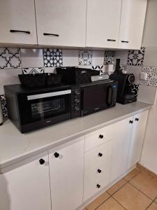 eine Küche mit weißen Schränken und einer schwarzen Mikrowelle in der Unterkunft saint cyprien in Saint-Cyprien