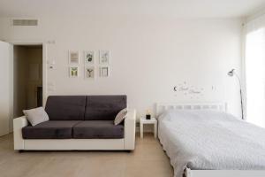 a white bedroom with a bed and a couch at Ca' Borsa II - Angolo nascosto nel cuore di Treviso in Treviso
