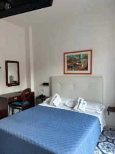 a bedroom with a blue bed and a desk at Hotel America in Marina di Camerota