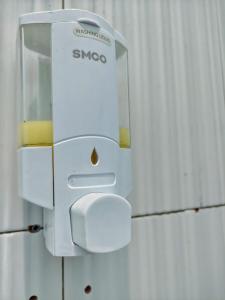 a white soap dispenser hanging on a wall at NgeKost harian in Alastuwo