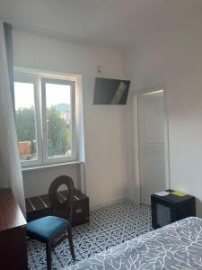 a bedroom with a bed and a chair and a window at Hotel America in Marina di Camerota