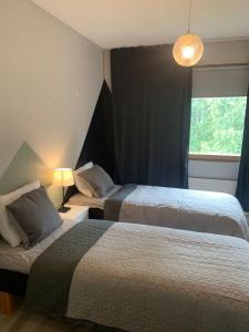Un dormitorio con dos camas y una lámpara y una ventana. en Tuohilinna, en Rovaniemi