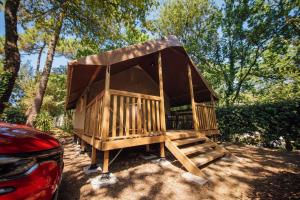 a large wooden gazebo sitting next to a car at Camping Les Pins de la Coubre in Les Mathes