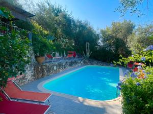 a swimming pool with two red chairs next to it at Casa Del Sole in Camaiore