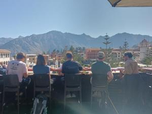 a group of people sitting at a table with mountains in the background at Cabanaconde Backpackers - Plaza de Armas in Cabanaconde