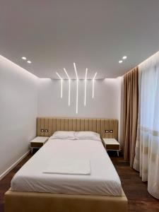 a bedroom with a large bed and a chandelier at HRS luxury apartments 102 in Durrës