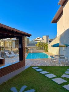 Un patio trasero con piscina, mesa y sillas. en Casa no Centro de Águas de Lindóia com Piscina, en Águas de Lindóia