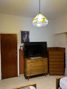 a living room with a tv and a dresser and a light at Casa con pileta in Tandil
