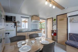 Mobil home proche du paradis des plages في سان جان دي مونت: مطبخ وغرفة طعام مع طاولة وكراسي