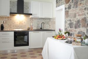 a kitchen with white cabinets and a table with fruit on it at B&B Aquas in Sardara
