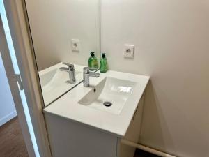 un bagno con un lavandino bianco e uno specchio di Charmant 2 Pièces avec Parking Près de Paris by Immo Kit BNB a La Courneuve Altre 30 foto