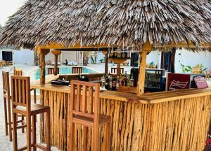 a bar with two chairs and a straw hut at GARDEN EDEN Lodge in Jambiani