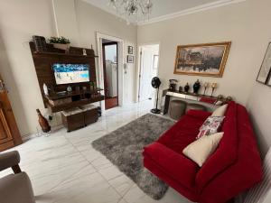 a living room with a red couch and a tv at Apartamento Fontana di Trevi Centro Serra Negra in Serra Negra +13 photos