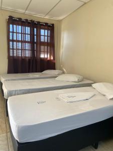 a group of three beds in a room with a window at Elache Plaza Hotel in Roseira