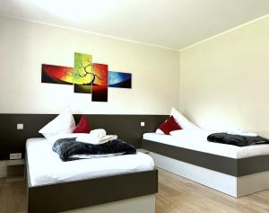 two beds in a room with paintings on the wall at Geschmackvolle moderne Apartment-Wohnungen in Hünfeld