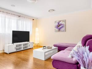 a living room with a purple couch and a tv at Spacious Central located Family House at Sunnybank in Brisbane