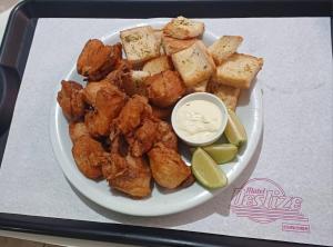 a plate of food with chicken and tofu and a dipping sauce at Deslize Motel in Curitiba