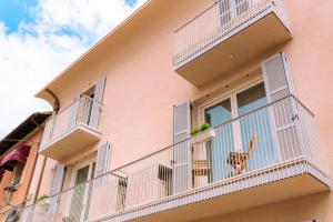 ein rosafarbenes Gebäude mit weißen Balkonen und ein Stuhl auf einem Balkon in der Unterkunft Borgo Cavour Luxury Apartments - Centro storico in Fano