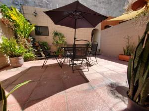 Una mesa y sillas con una sombrilla en un patio. en Kokys Guest House, en Nueva San Salvador 1 foto más