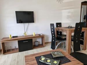 a living room with a table and a tv on a wall at Apartman Curcic 1 in Soko Banja