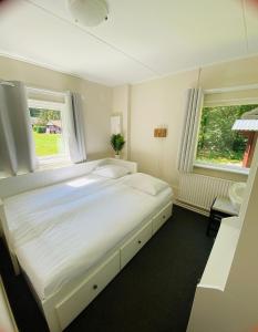 a white bed in a room with two windows at Morning Glory, Huisje vogelzang in Beekbergen