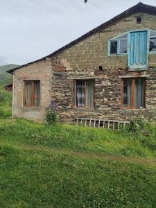 an old brick house with blue doors and windows at Guest House Cafe Nita in Ushguli