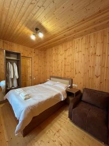 a bedroom with a large bed and a chair at Villa Mzetamze in Borjomi