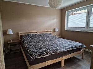 a bedroom with a bed with a black and white comforter at Apartament Sosny 2,1 nad jeziorem OTW Borówno Wielkie in Skarszewy
