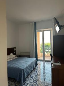 a bedroom with a bed and a sliding glass door at Hotel America in Marina di Camerota
