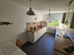 una cucina con mobili bianchi, un tavolo e una finestra di FeWo Heppenheim a Heppenheim