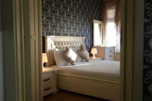 a bedroom with a white bed with blue wallpaper at Villa Livia Boutique Apartments in Ravda