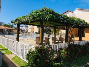 a gazebo with a white fence and flowers at Apartamento sofisticado com piscina e vista privativa in Ilhéus