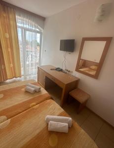 Zimmer mit 2 Betten, einem Schreibtisch und einem Spiegel in der Unterkunft Concordia Plaza 2 in Primorsko