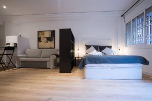 a white bedroom with a bed and a couch at Bcn - Loft Parc Guell in Barcelona
