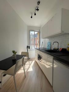 a kitchen with white cabinets and a table and a sink at ​Cœur de ville ! Cœur de l'Oise​​ ! Moderne & fonctionnel​ in Clermont