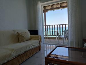 a living room with a couch and a balcony at Seafront Apartment Pefkochori in Pefkochori +7 photos