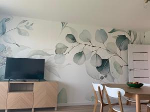 Ein Wohnzimmer mit Fernseher und einem Baumgemälde an der Wand in der Unterkunft Smile 2 in Tomice