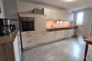 a large kitchen with white cabinets and a window at Urlaub in Duckwitz - Familienfreundliche Ferienwohnung in Seenähe in Behren-Lübchin