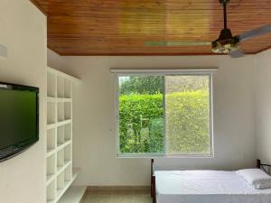 a room with a window and a bed and a television at Acogedora casa de descanso con piscina privada in Melgar