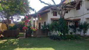 a white house with a tree in the yard at Chalé Charmoso das Ubaias in São Miguel do Gostoso