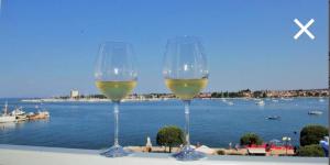 two glasses of wine sitting on a ledge overlooking the water at Umagic Apartment in Umag